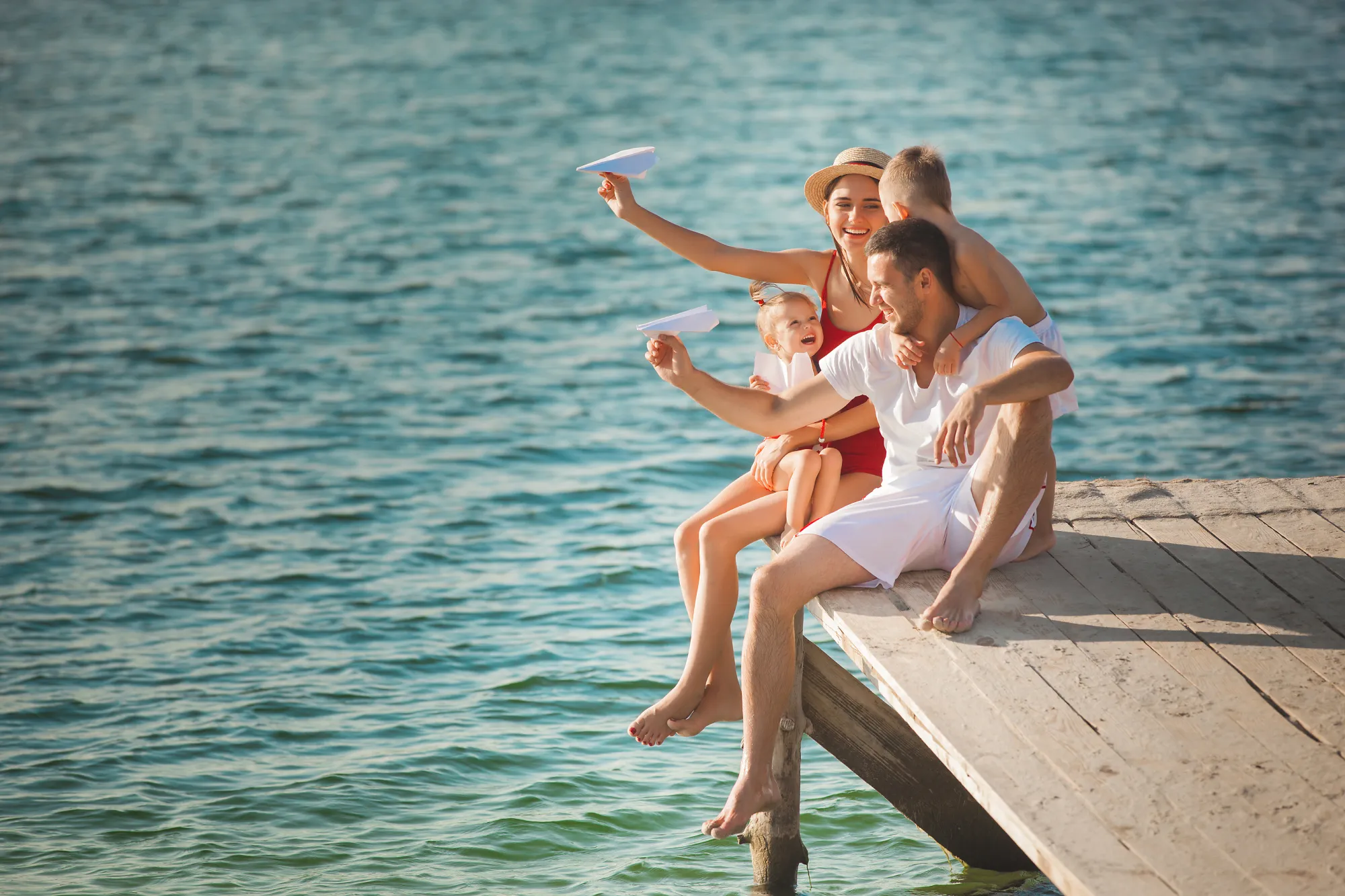 Happy cheerful family at the pier near the water having fun. Adorable kids playing with their parents